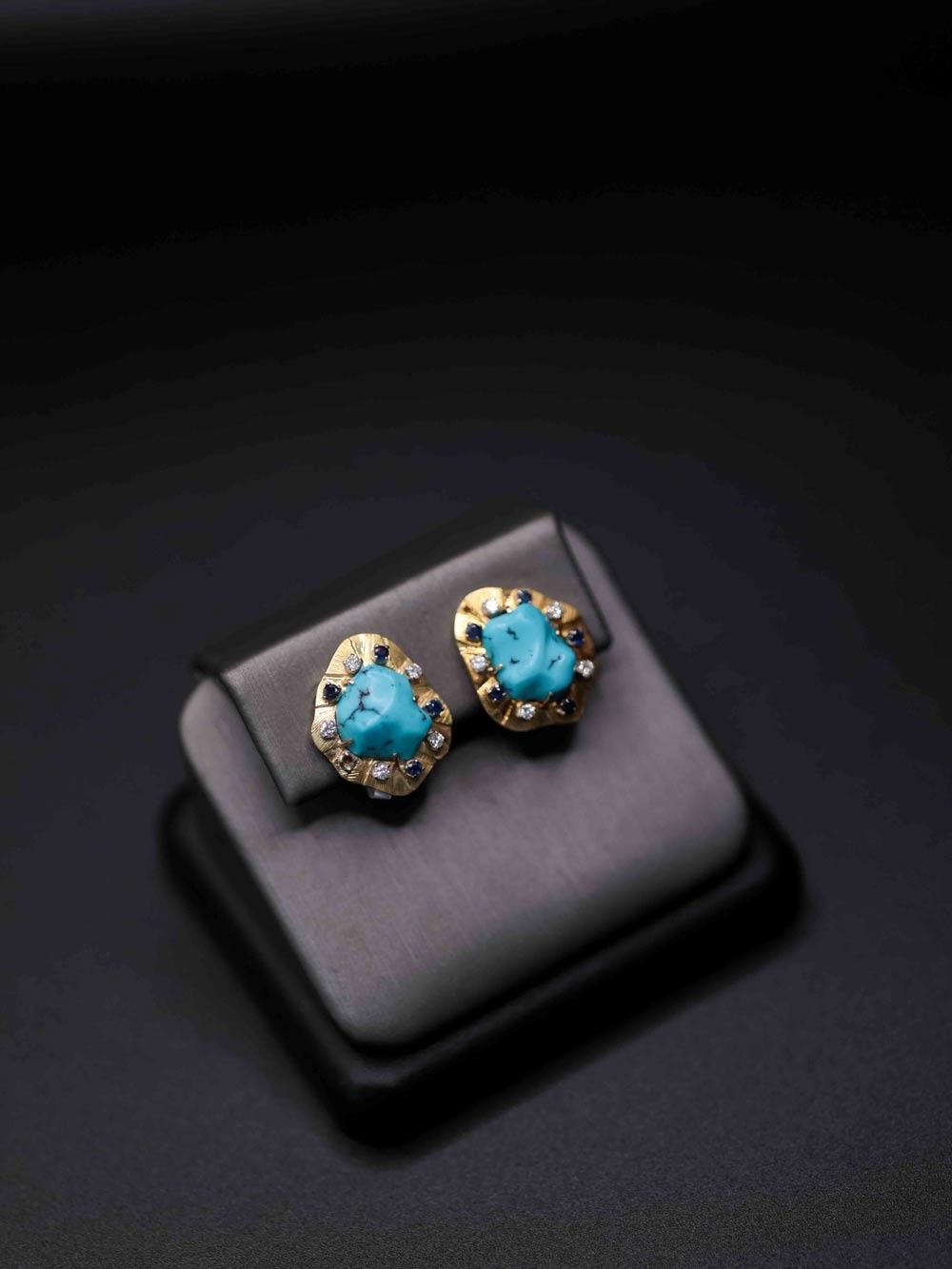 Pair of turquoise stud earrings on a black display cushion