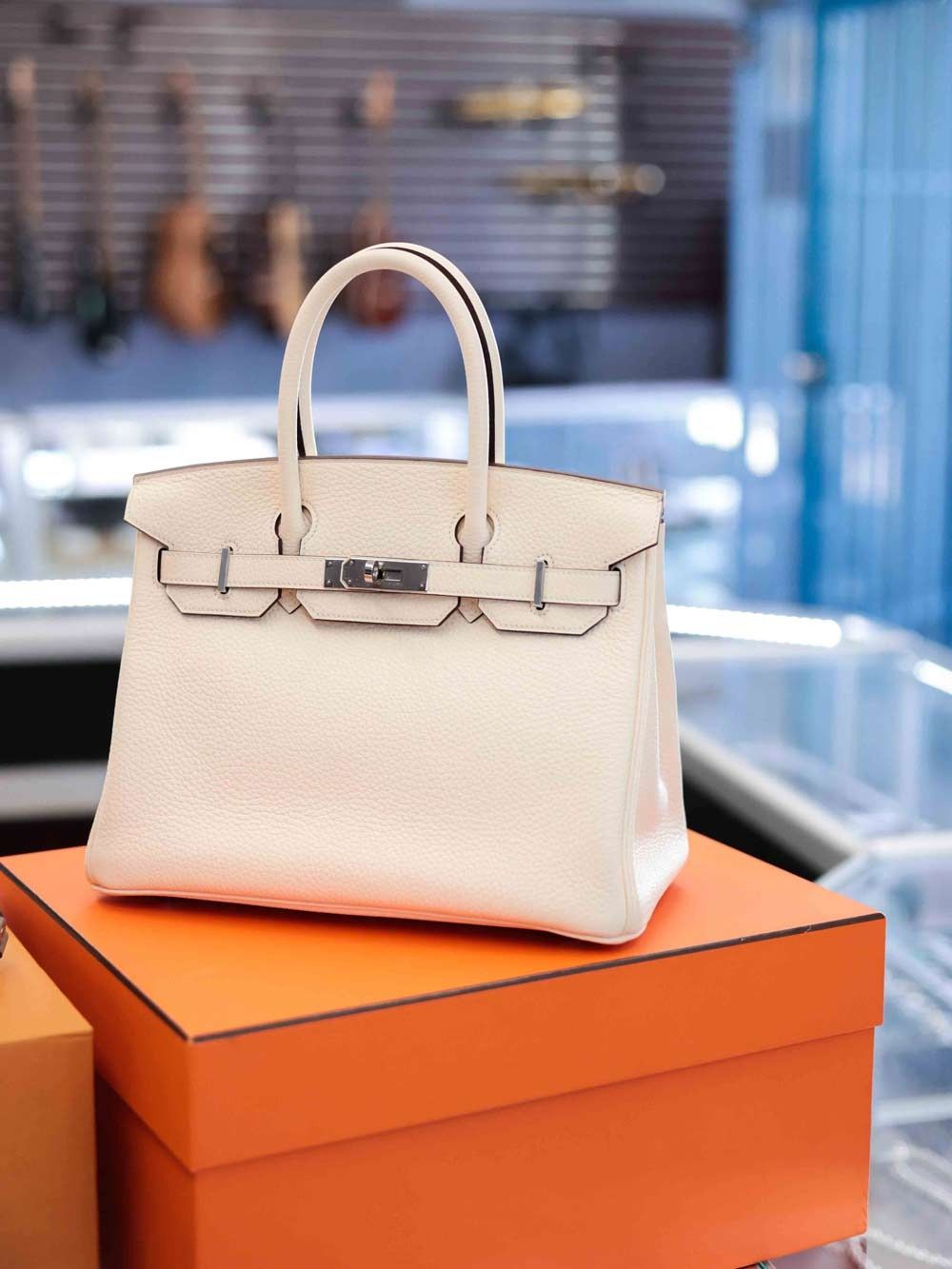 White handbag on stacked orange boxes in a boutique setting