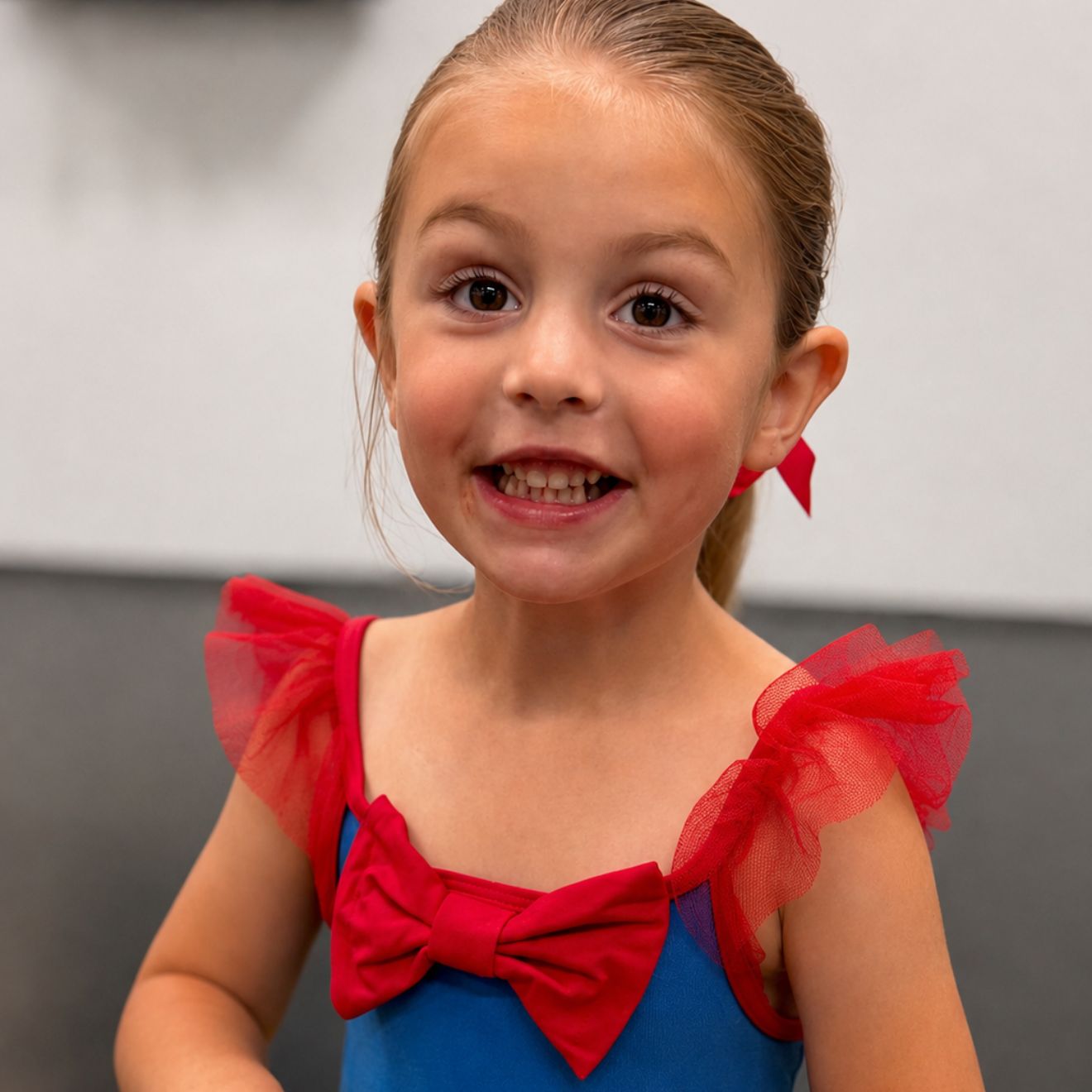 Young child in a red-and-blue costume smiling against a gray background