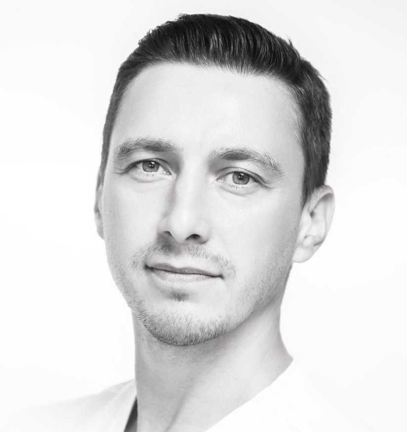 Black-and-white headshot of a person with short dark hair and a slight smile