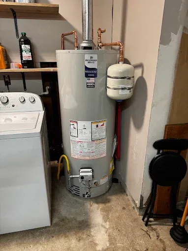 Water heater in a laundry room beside a washer and dryer