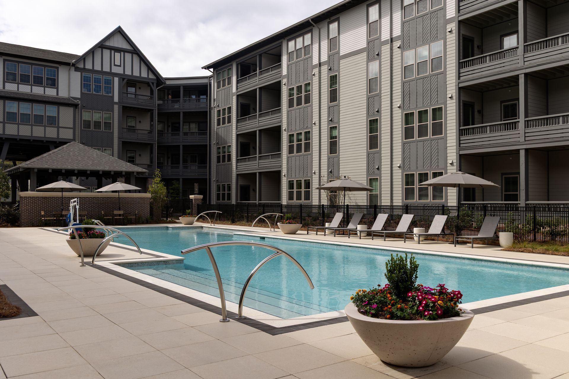Pool at apartment complex with lounge chairs and decorative planters.