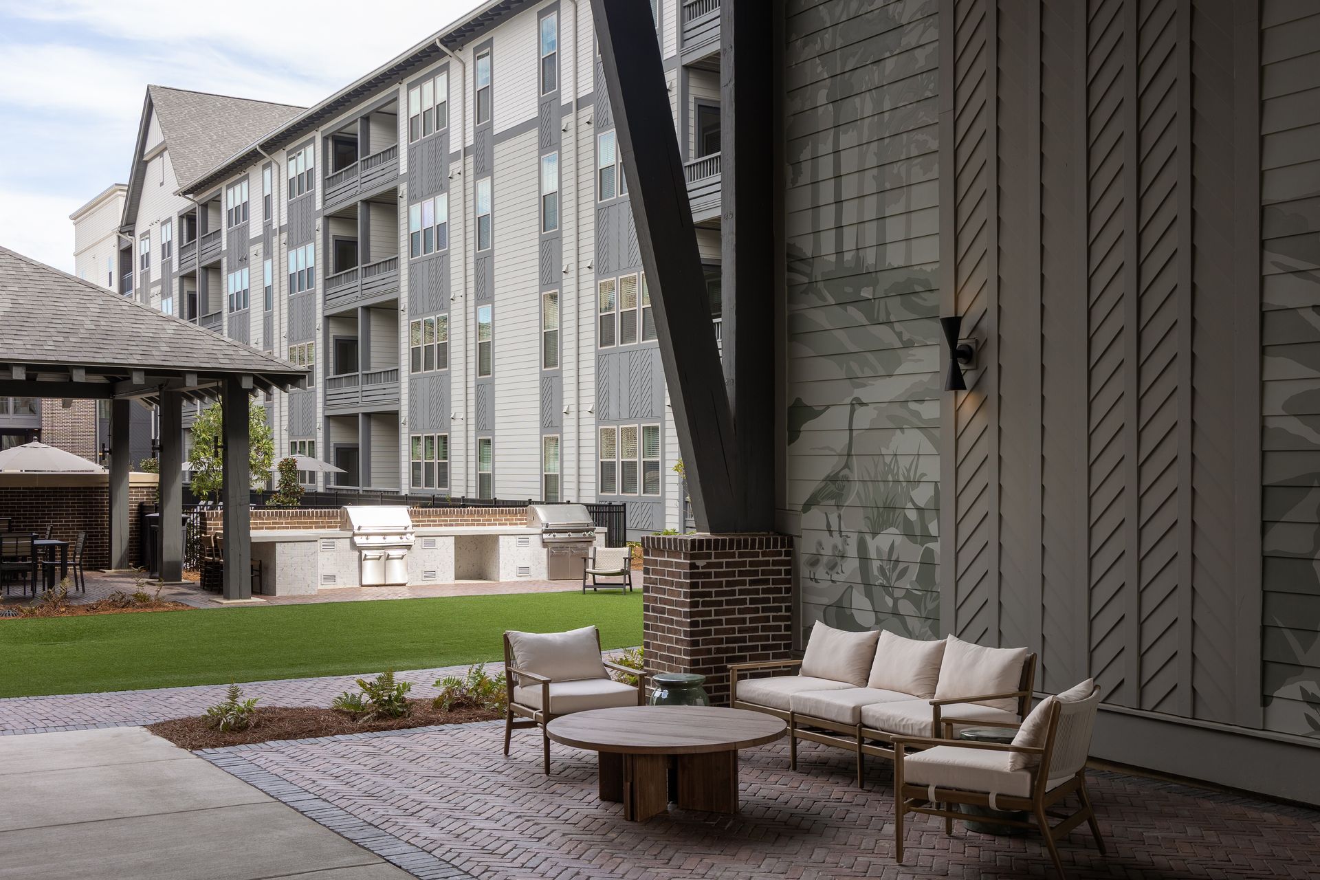 Outdoor patio with seating, grilling area, and multi-story building in the background.