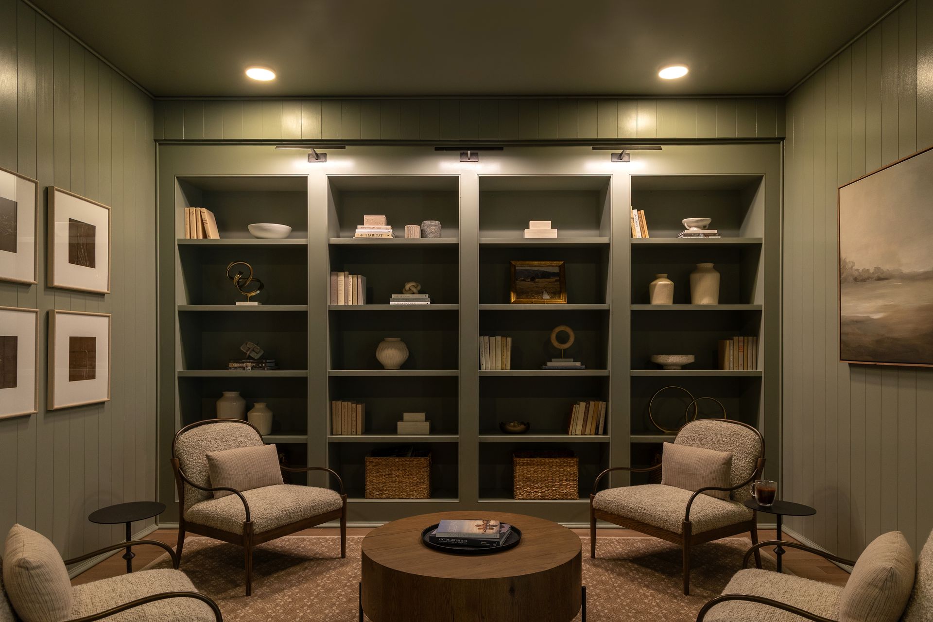 Cozy reading room with built-in bookshelves, armchairs, and a round coffee table on a patterned rug.