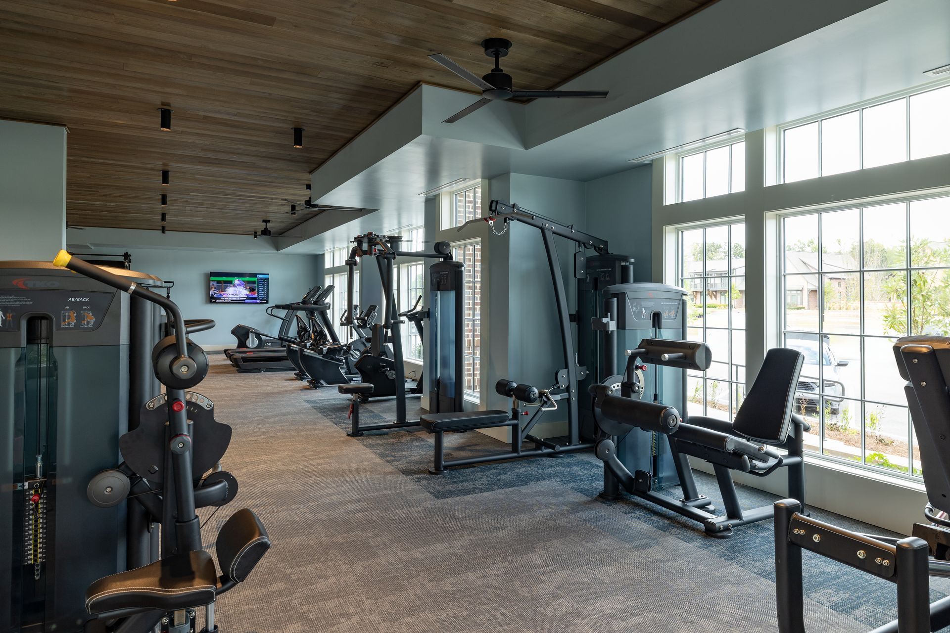 Gym with exercise machines, a tv, and a window.