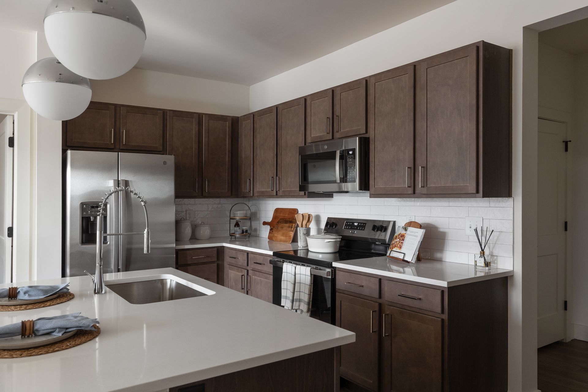 Modern kitchen with brown cabinets, stainless steel appliances, and white countertops.