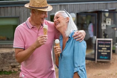Two people sharing ice cream and smiling outside a rustic building