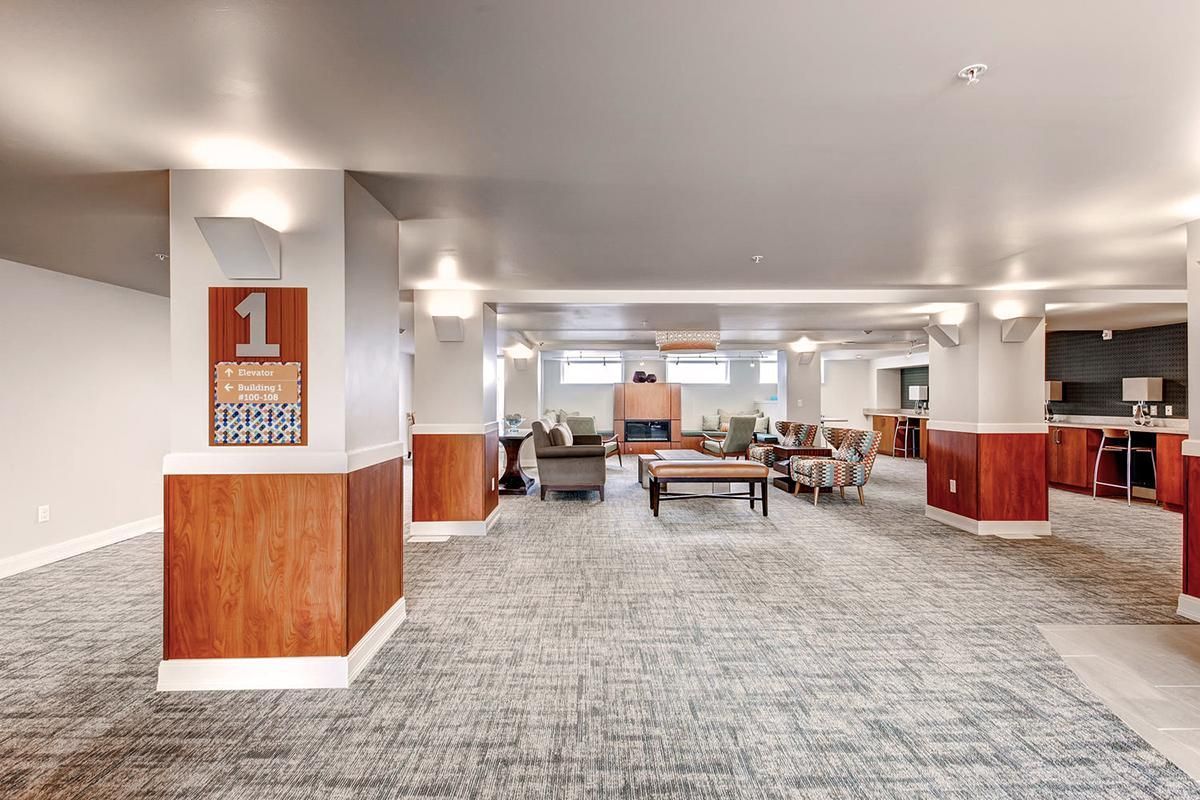 Spacious lobby with seating, fireplace, and patterned carpet. Sign for floor