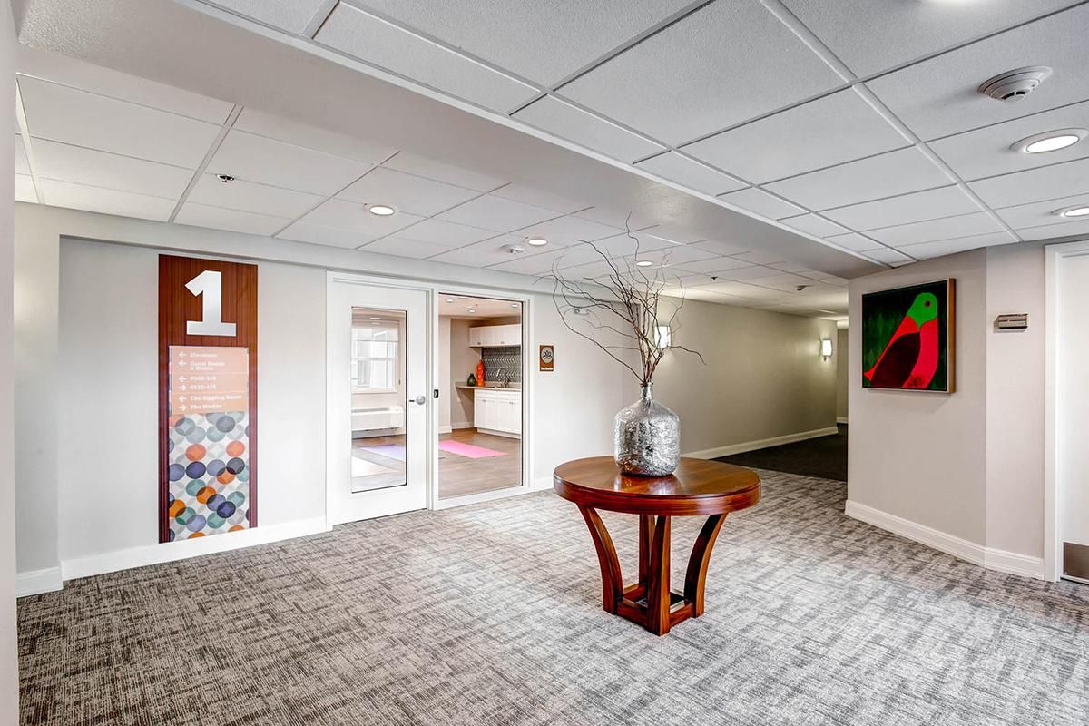 Hallway with a wooden table, artwork, and a door marked