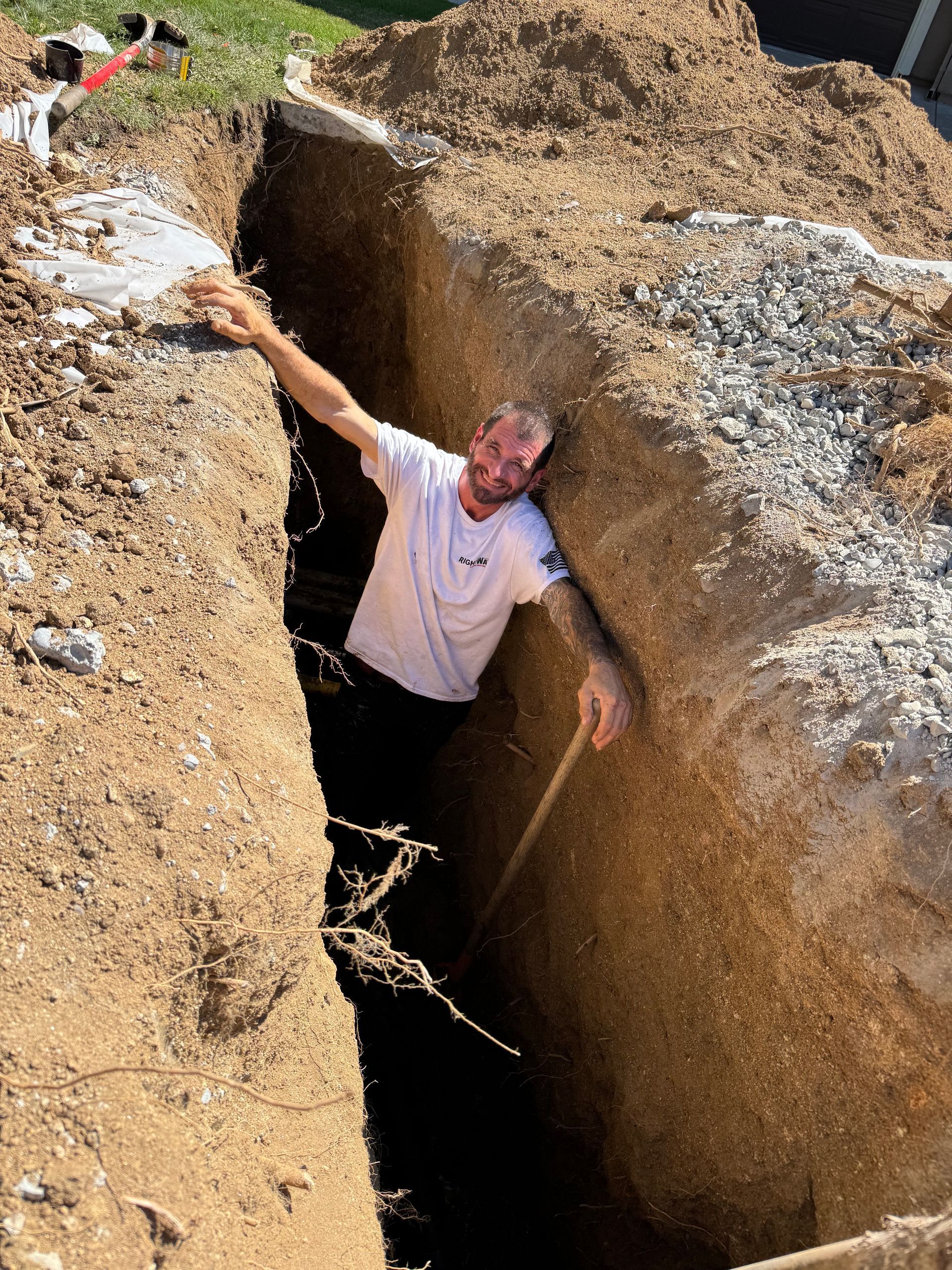 Rightway Plumbing Sewer And Drain - Man stuck in a narrow trench, arms outstretched, looking up with a worried expression.
