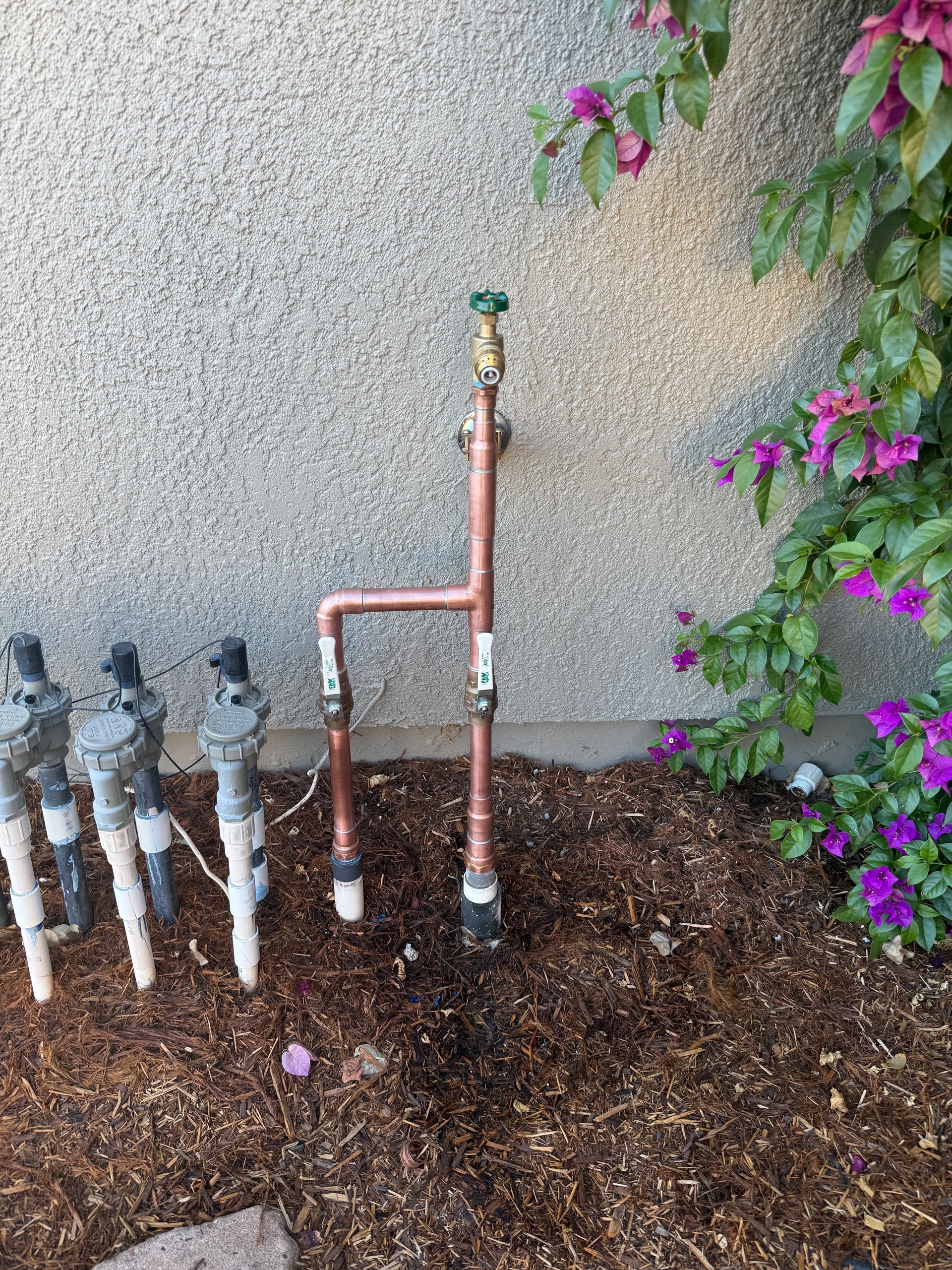 Rightway Plumbing Sewer And Drain - Copper irrigation system with faucet near stucco wall and sprinkler heads.