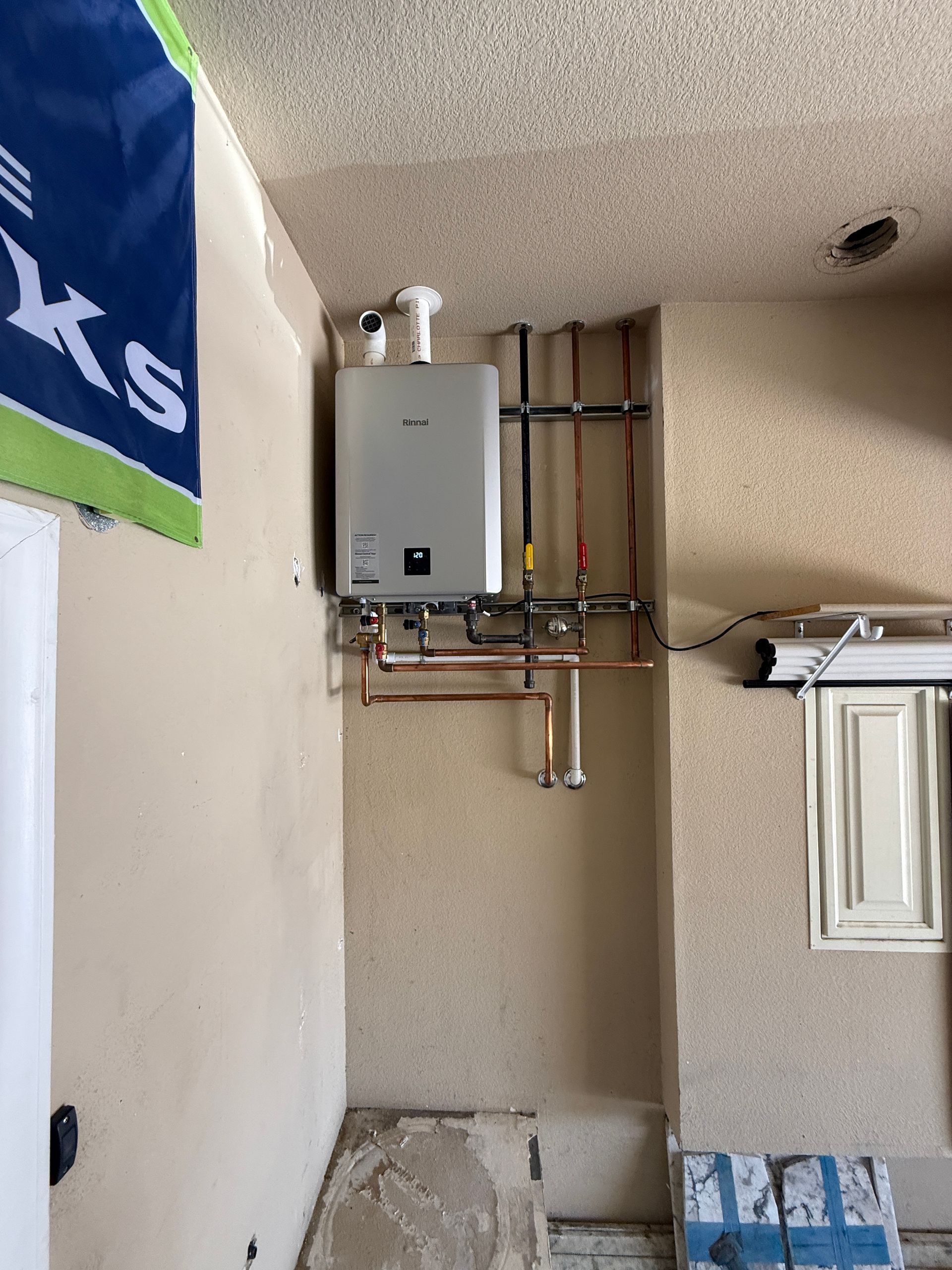 Wall-mounted water heater and exposed pipes in a utility nook above a doorway