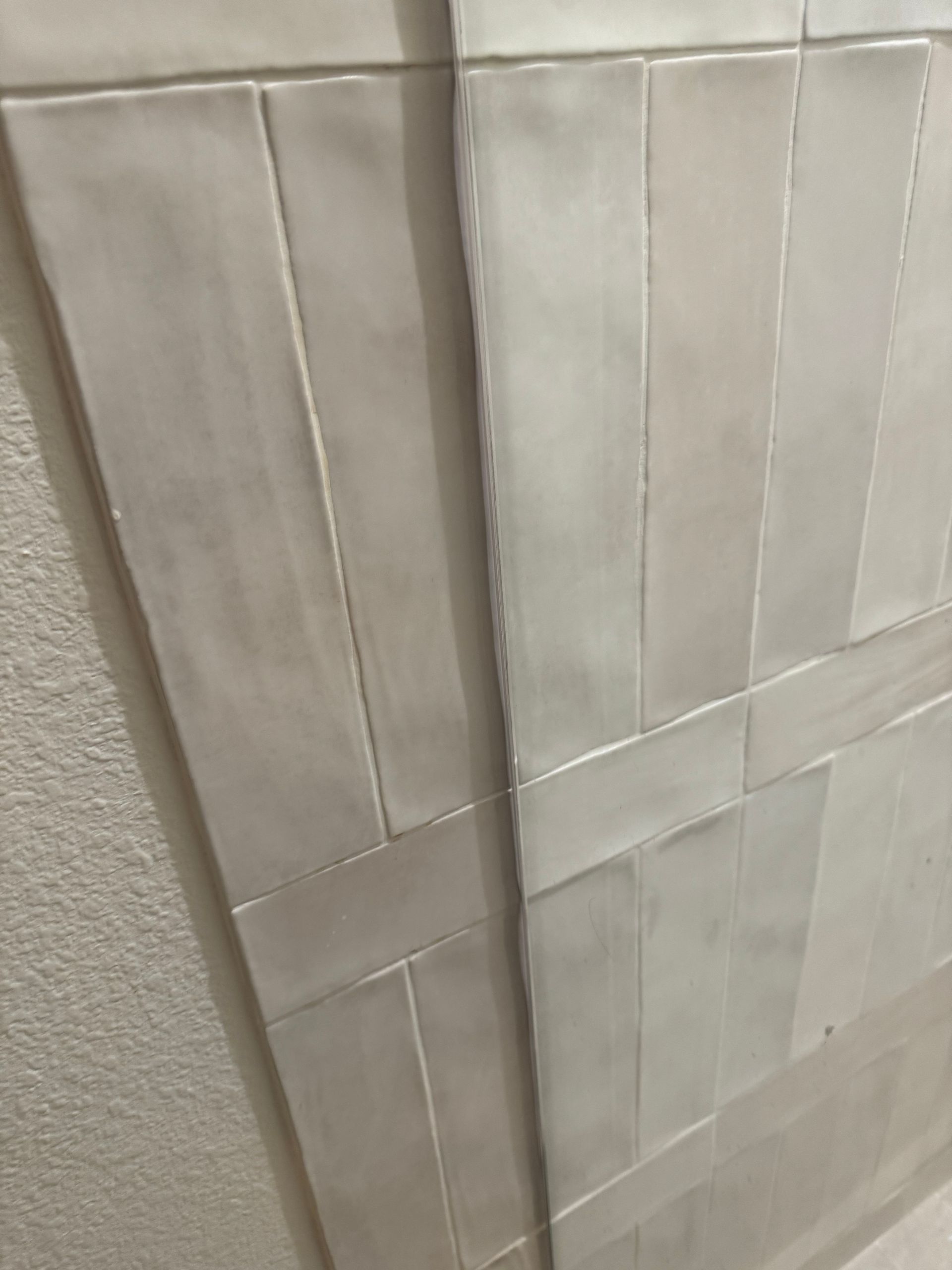 Close-up of a wall white rectangular tiles arranged in a decorative pattern, intersecting lines.