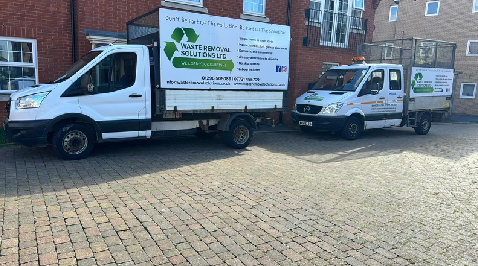 Two white trucks parked on cobblestones; one has a recycling logo and text.