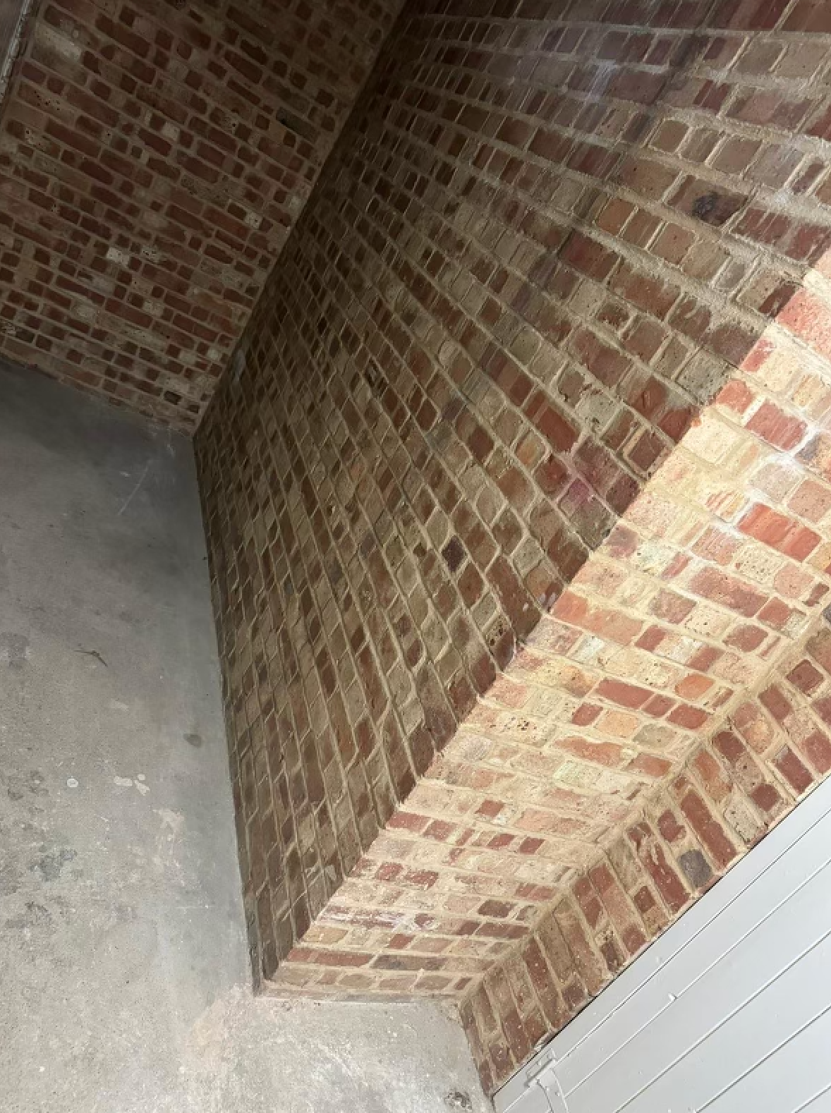 Brick archway and walls inside a building, with light hitting the red and brown bricks.