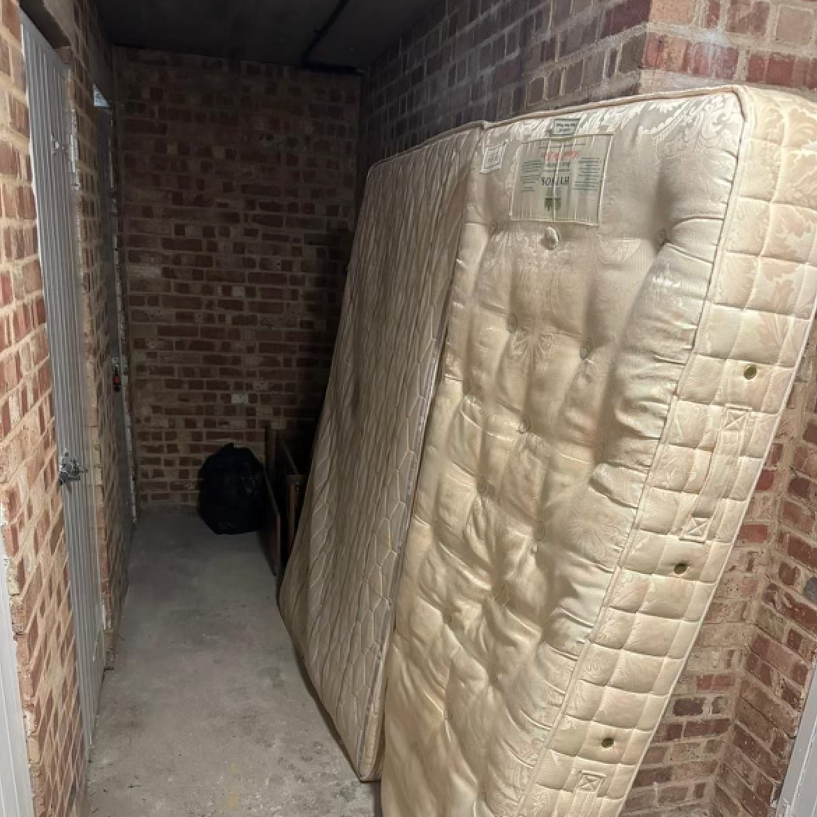 Mattress leaning against a brick wall in a storage unit.