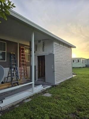 House exterior under renovation with ladder, scaffolding, and exposed siding on a porch area