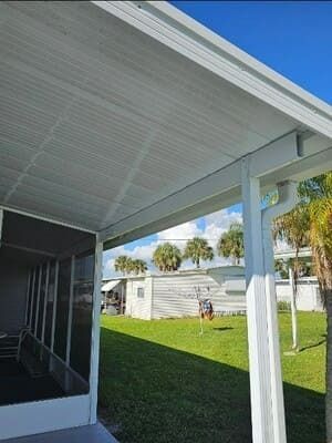 Covered patio overlooking a grassy yard with palm trees and a small white shed in bright daylight