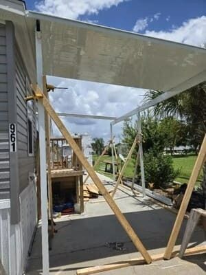 House exterior under construction with wooden supports and a white awning over a concrete walkway