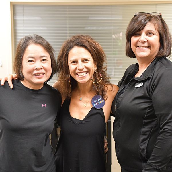 Three Hockessin Athletic Club staff members hugging and smiling