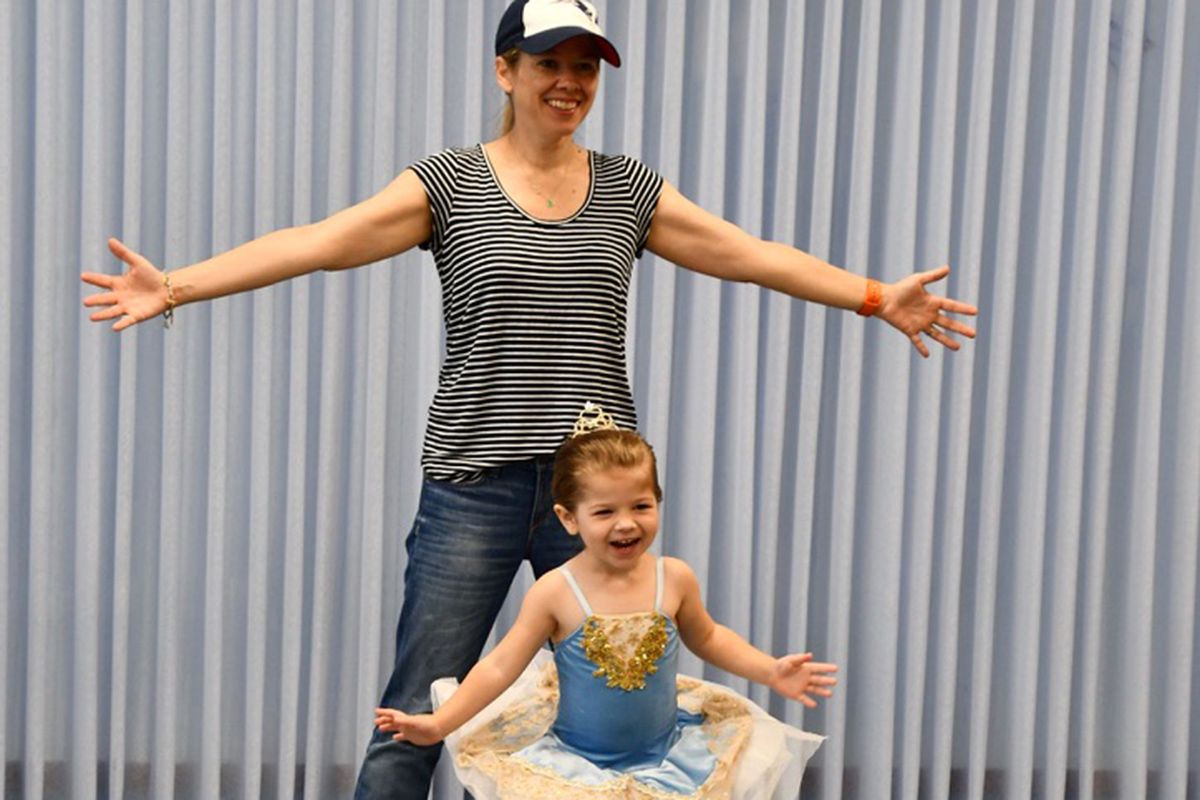 Mom holding young daughter and stretching on ballet barre