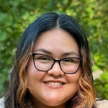 Jaileene, stylist at Whip Salon South Windsor, smiling outdoors in glasses