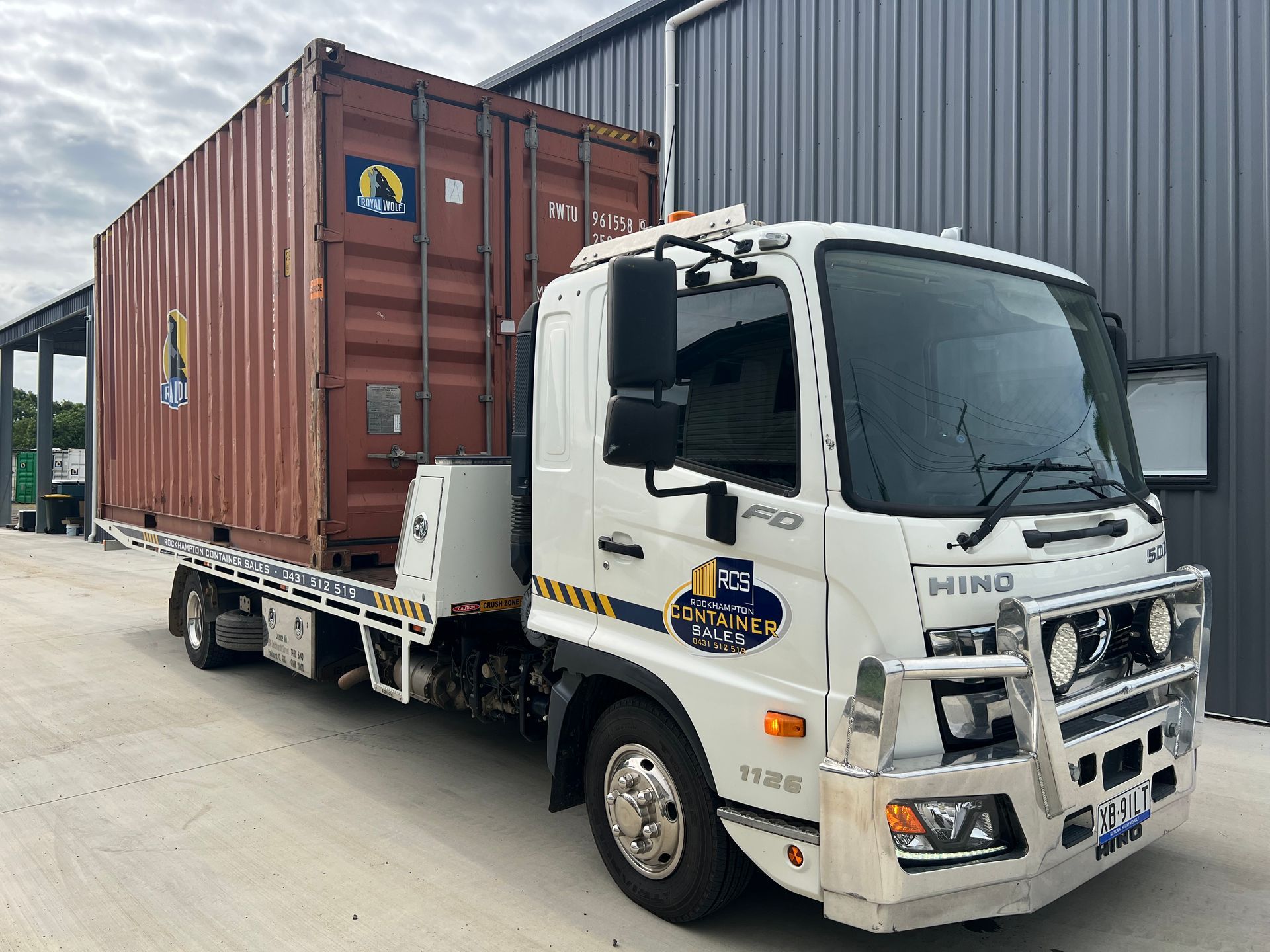 Shipping Container on a Flatbed Truck on Grassy Ground, Blue Sky — Rockhampton Container Sales in Kawana, QLD