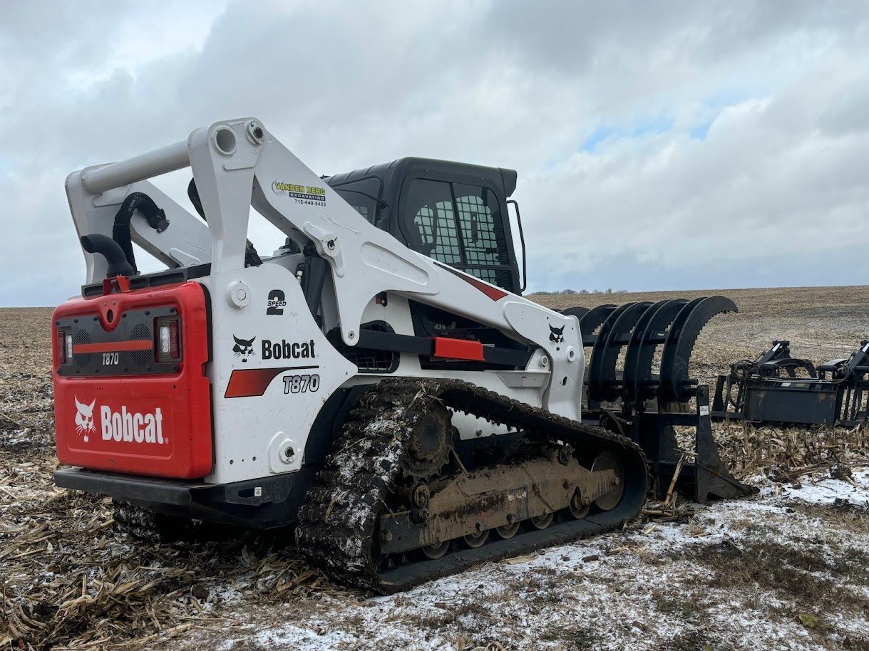 Red Bobcat track loader driving through muddy snow in an open field