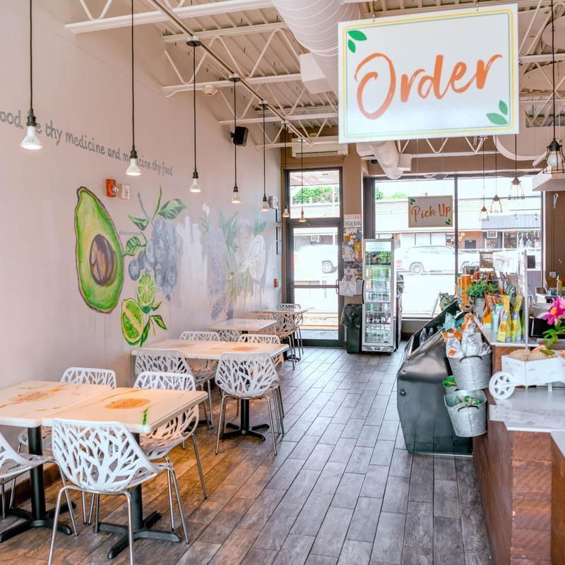 Bright, airy café interior with wooden tables, wall art, and an “Order” sign near the counter.