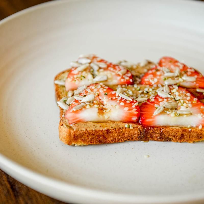 Toasted bread with sliced strawberries and sesame seeds on a white plate