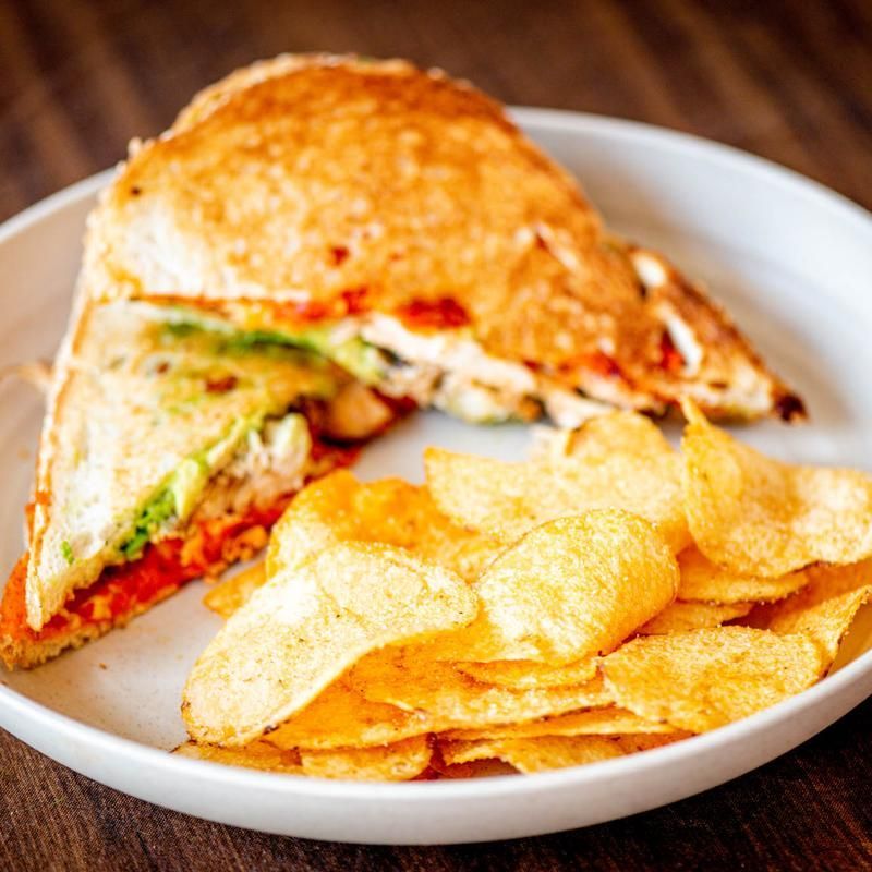 Sandwich with potato chips on a white plate on a wooden table