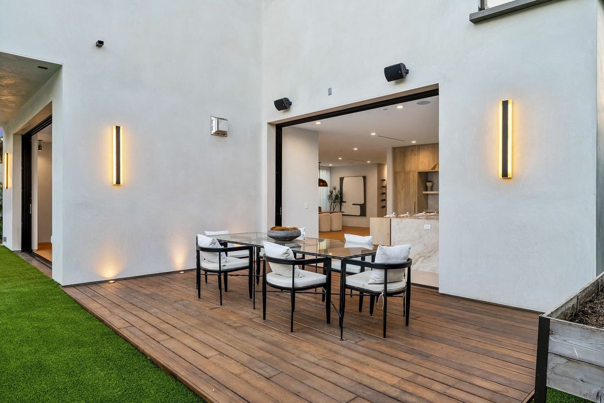 Modern patio with wooden deck, outdoor dining table and chairs.