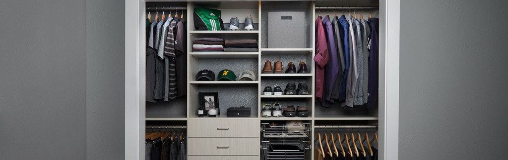 an organized reach-in closet system filled with clothes, caps, and shoes