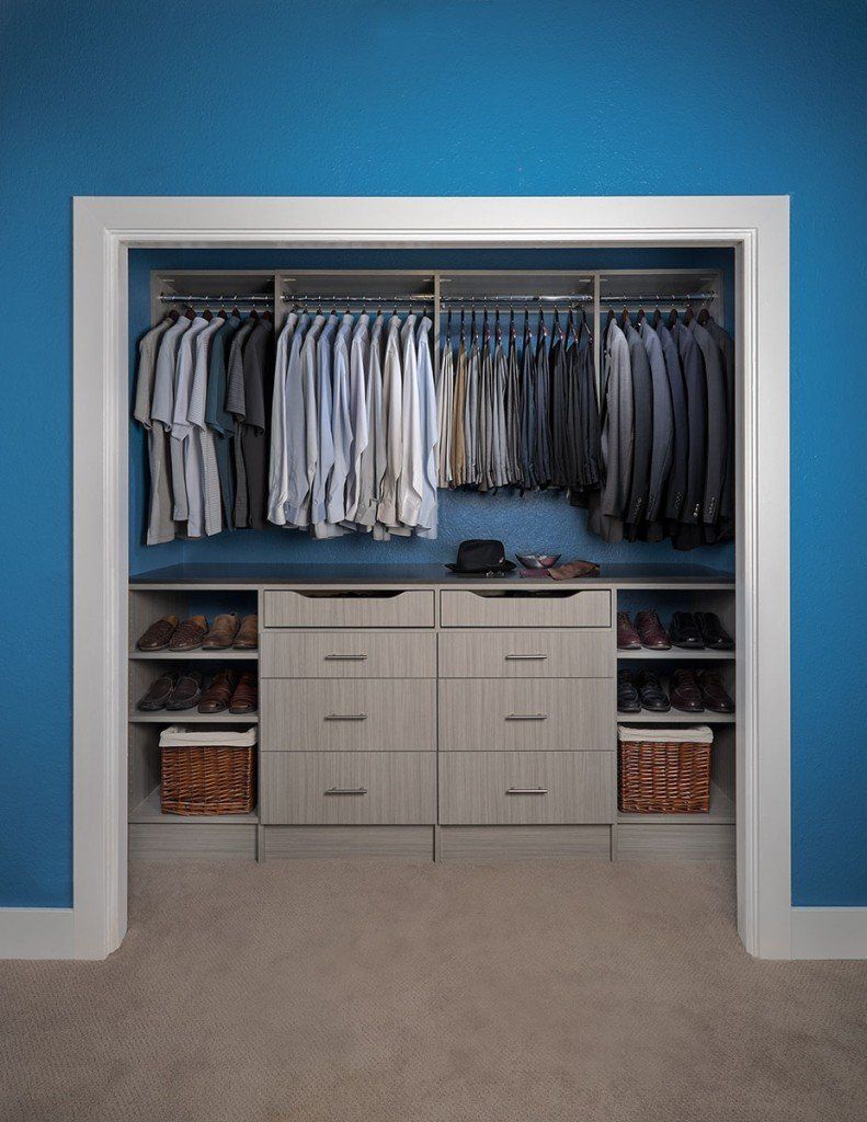 a walk in closet with blue walls and a shelving system filled with clothes .
