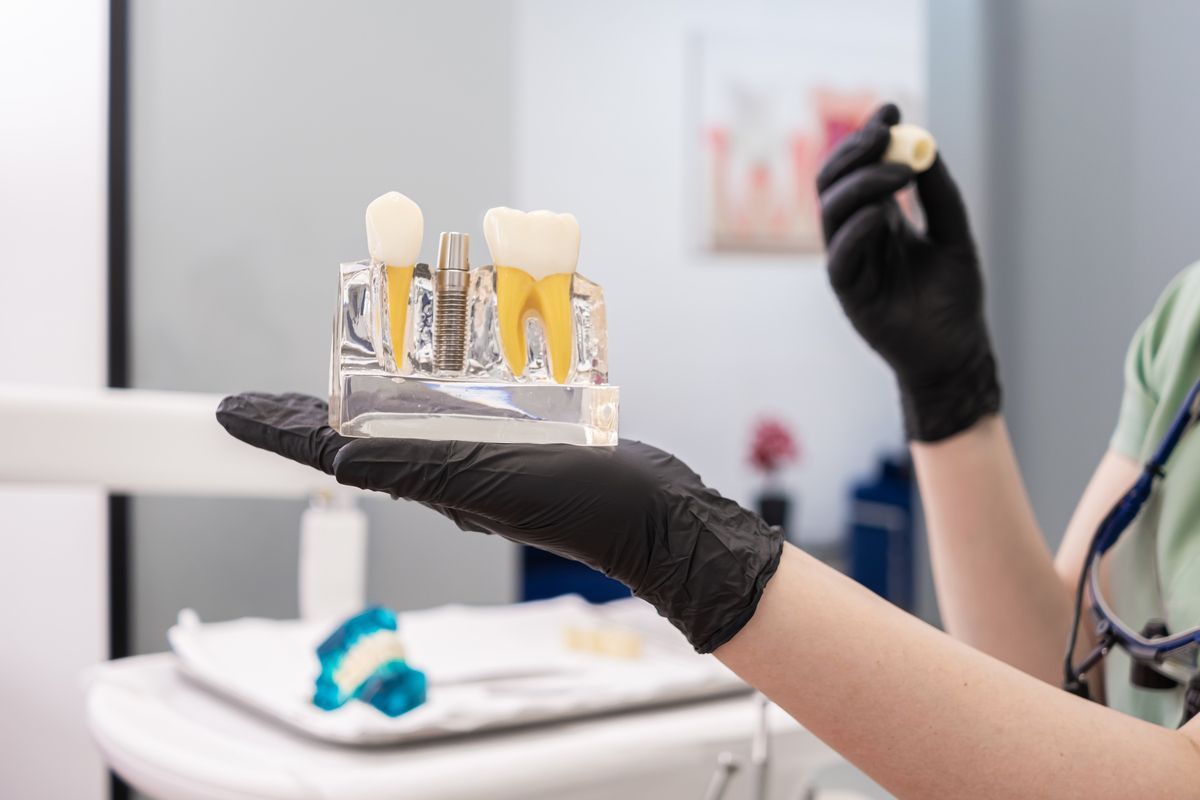 Gloved hand holding dental tooth models in a clinic setting