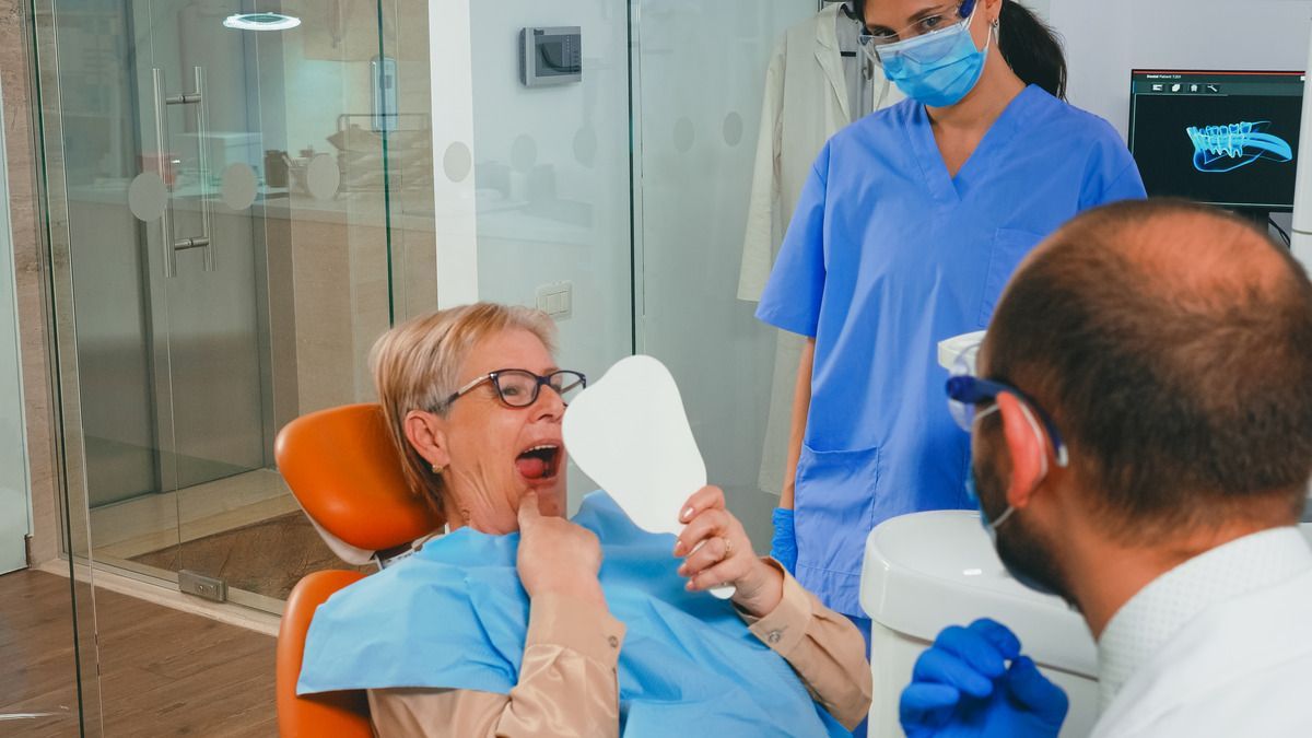 Enjoy dental implants from our top dentist near Longmont CO 80501 woman with new dental implants looking in mirror | Best dentist near Longmont CO 80501