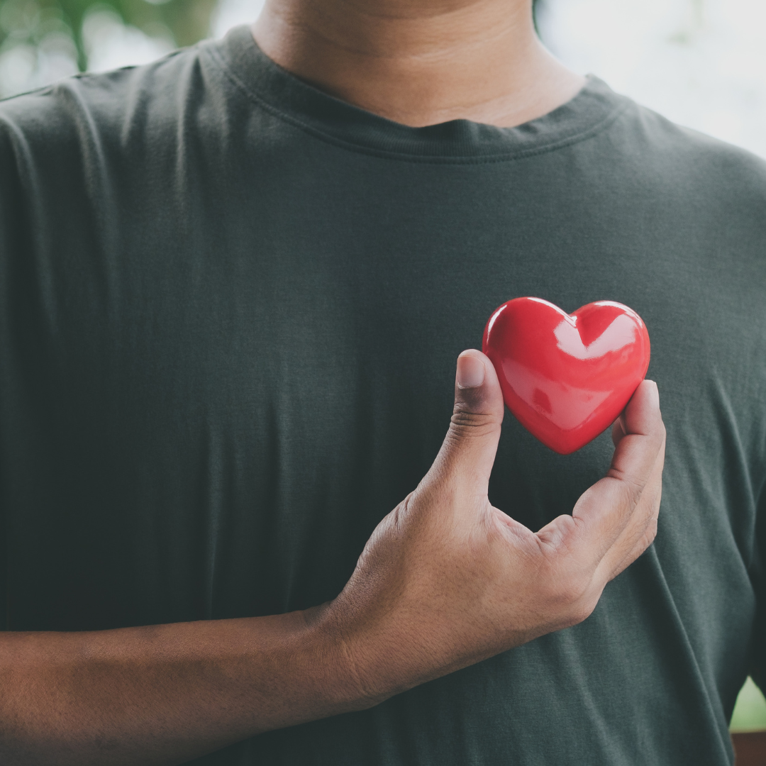 A man is holding a red heart in front of his chest
