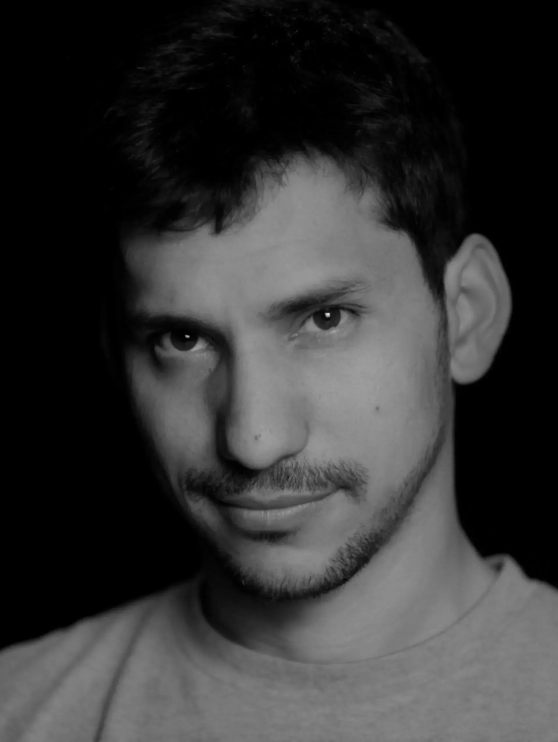 Un hombre con barba sonríe en una foto en blanco y negro.