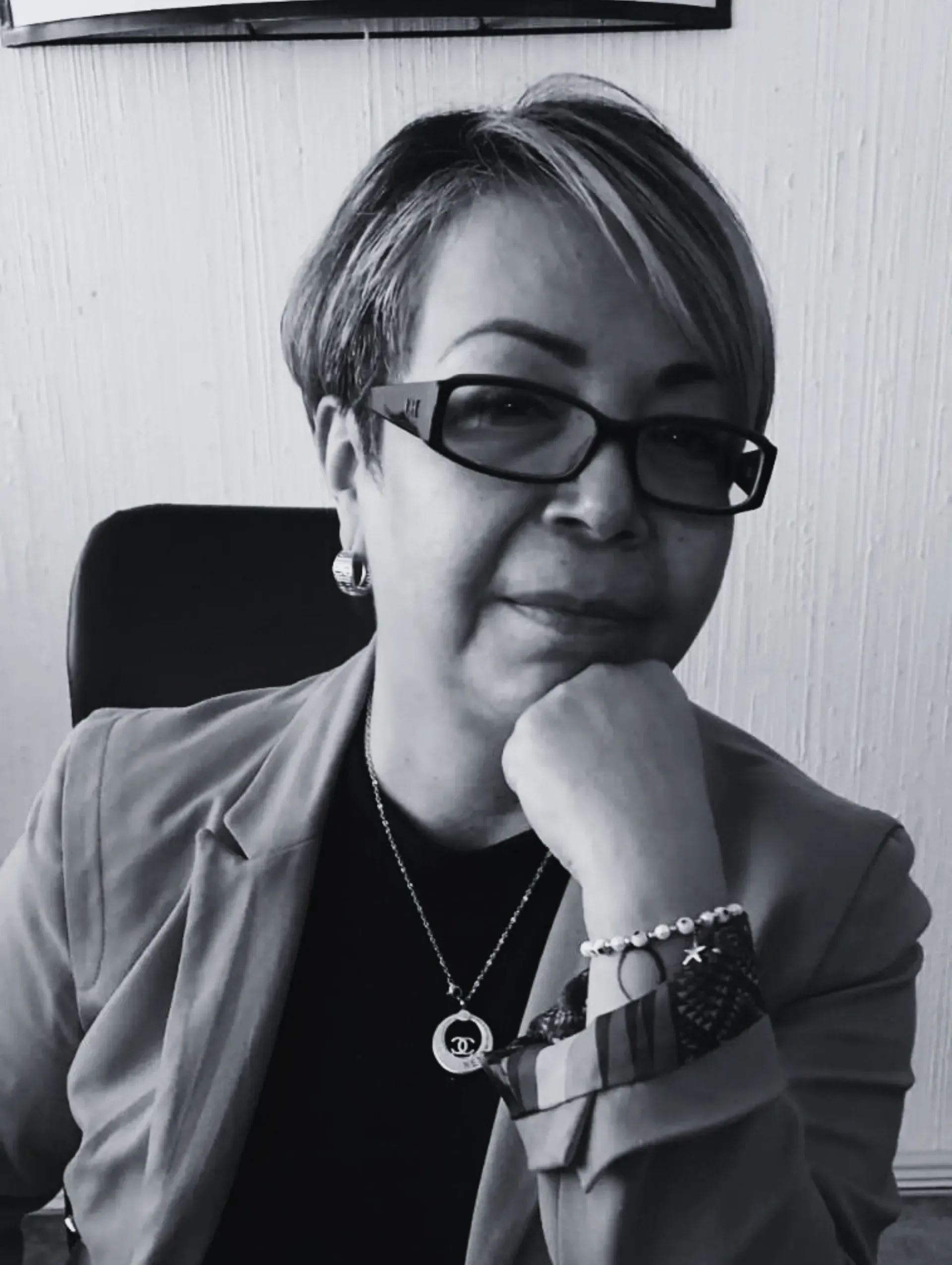 Una fotografía en blanco y negro de una mujer con gafas y un collar.