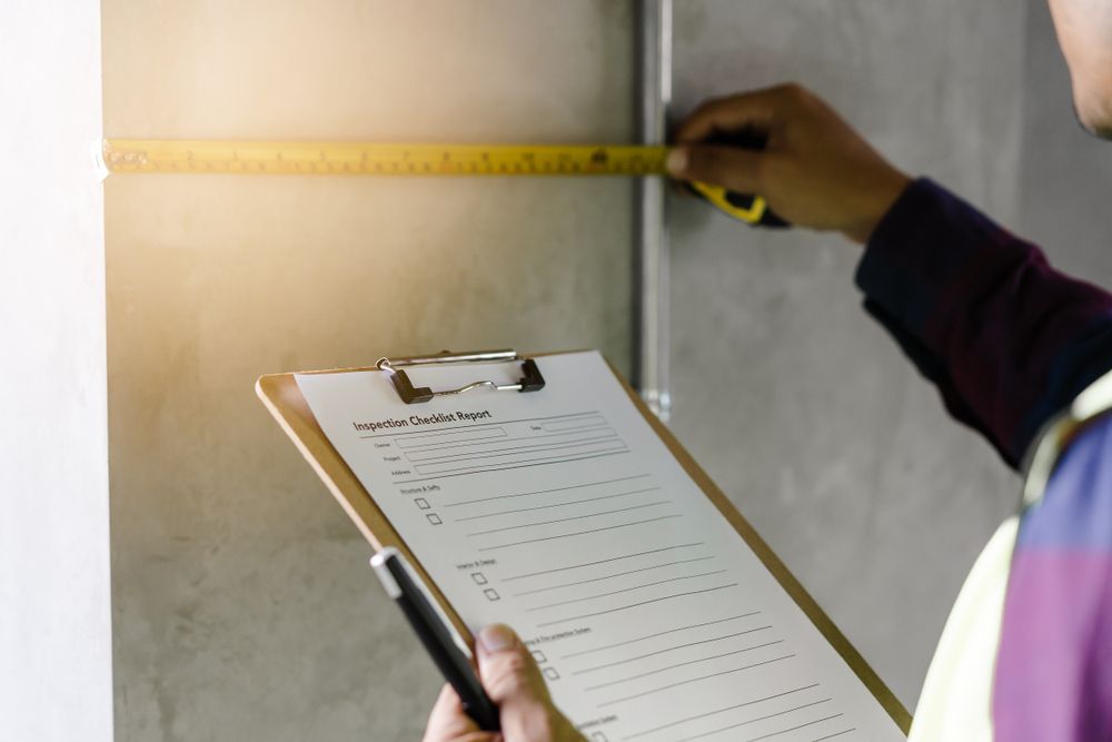 Person Measuring Wall With Tape, Holding Clipboard With Data Sheet — Property Transfer Professionals In Gosford, NSW