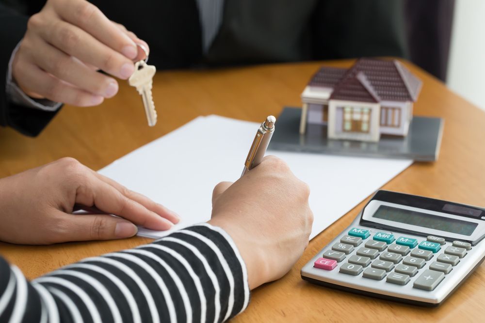 Hands Exchanging House Keys Above a Signed Document — Property Transfer Professionals in Wyong, NSW