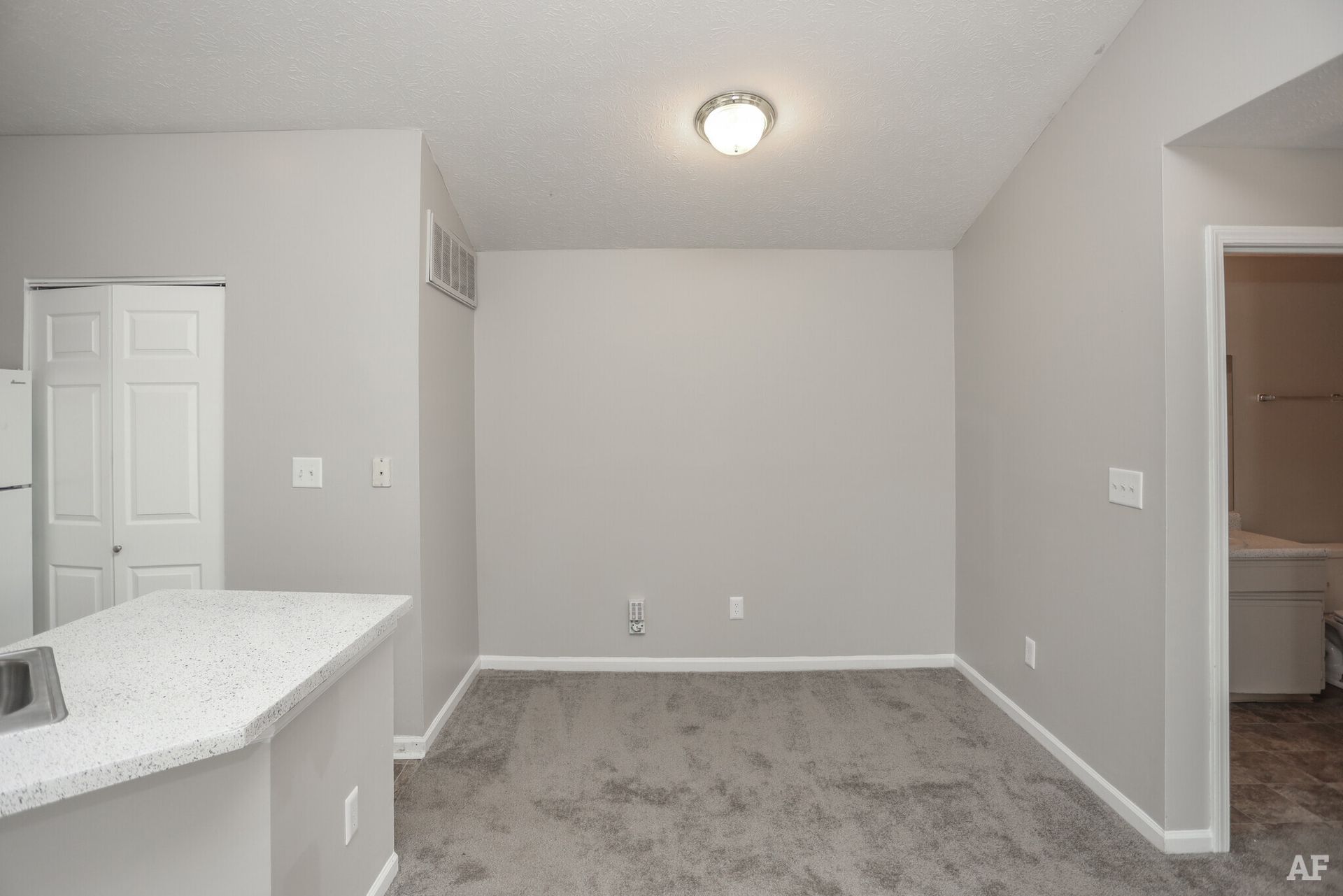 Empty room with gray walls and carpet, white trim, and a granite countertop.