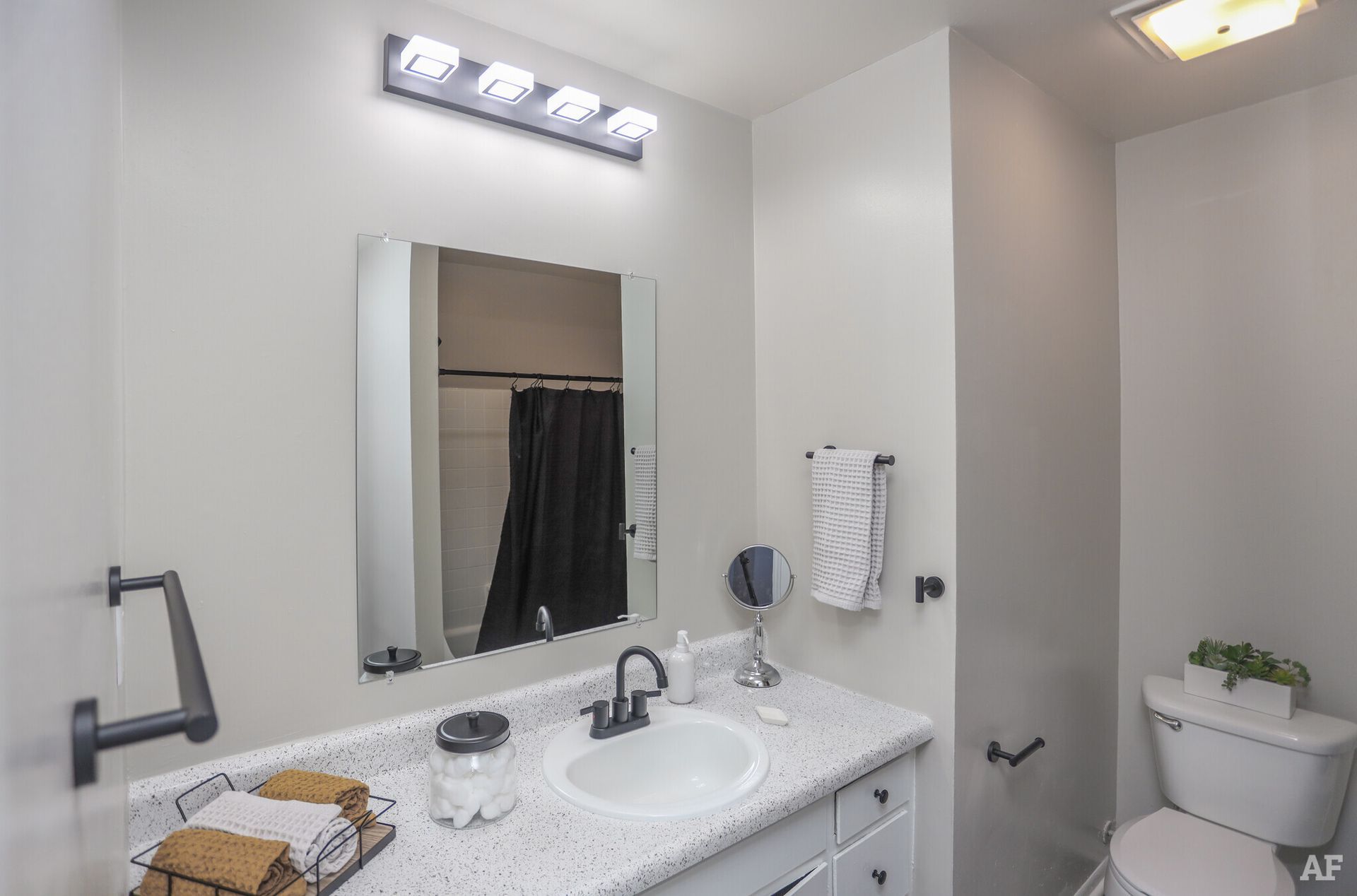 Bathroom with gray walls, white vanity, mirror, and black accents, including towel rack and fixtures.