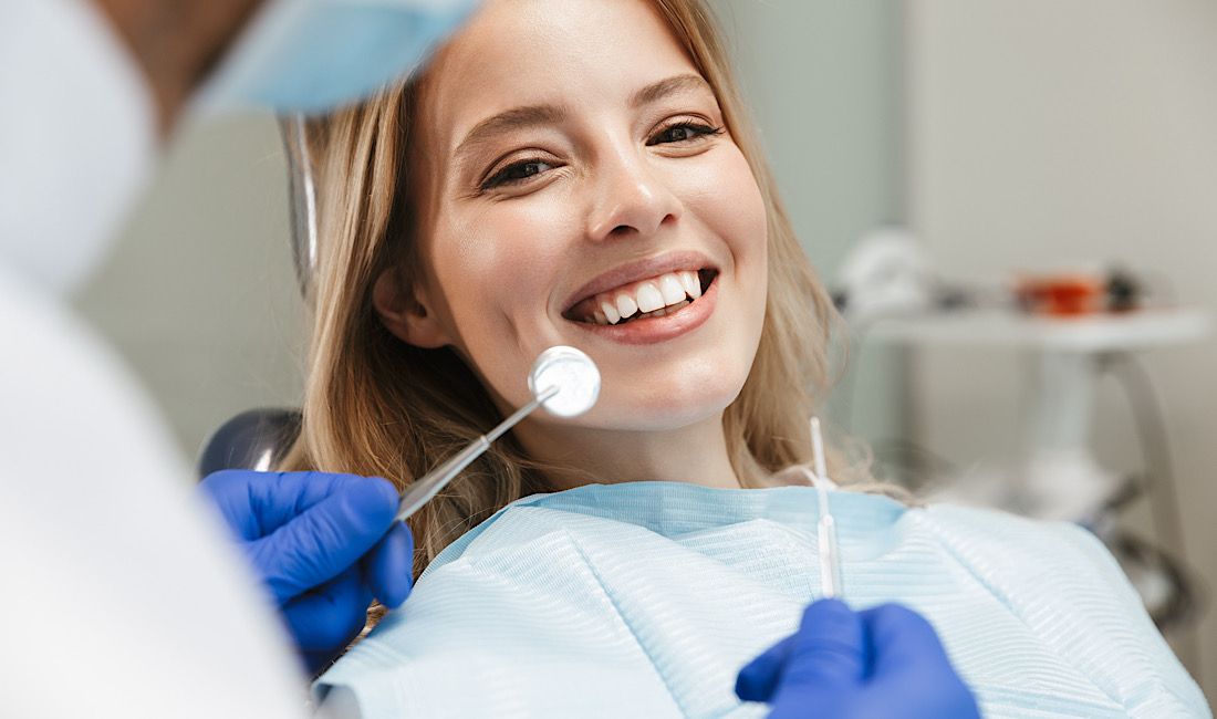 Woman sitting in dental chair smiling while dentist examines her teeth for a new smile makeover in Salinas, CA.
