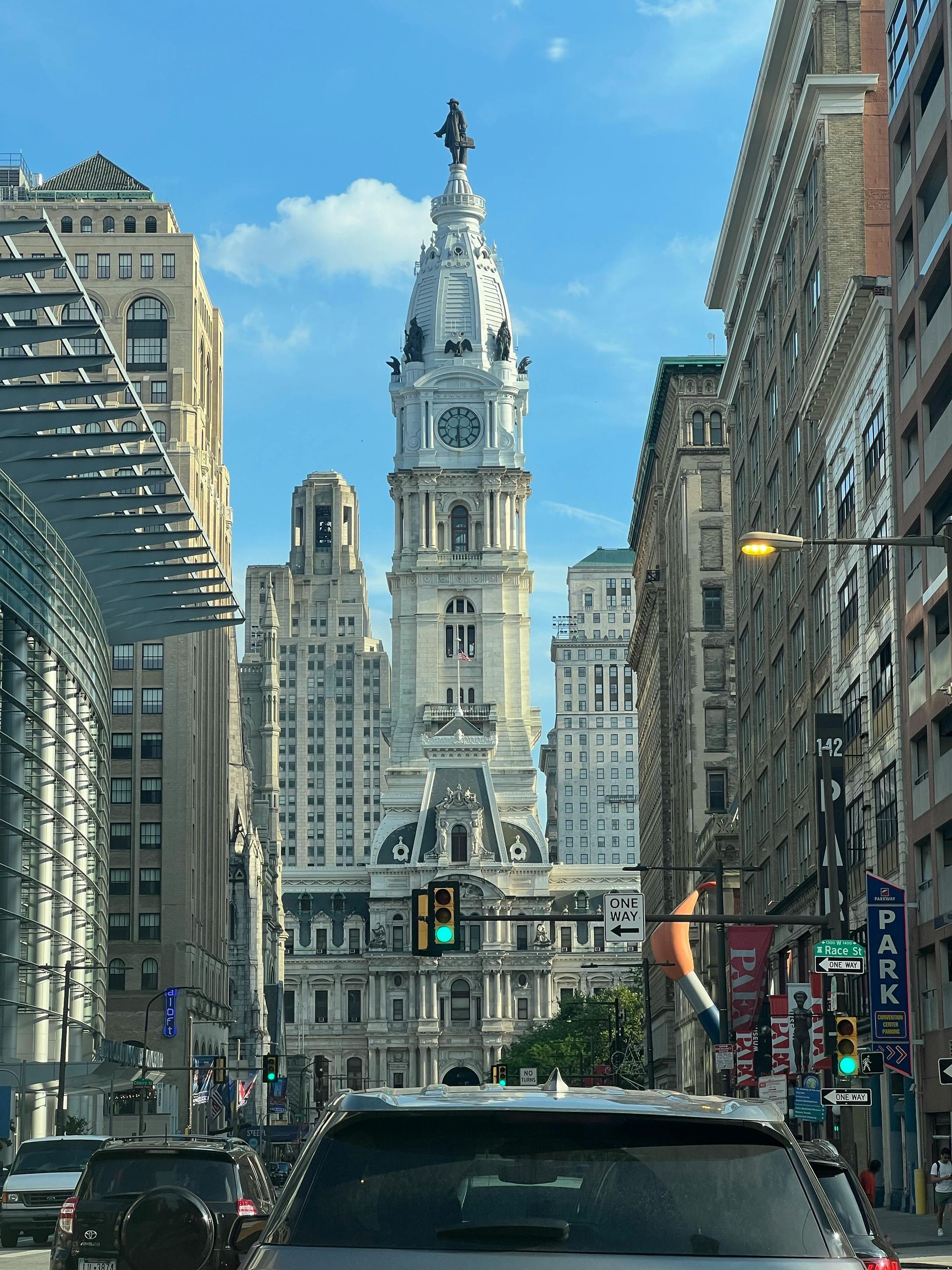 City street view with a tall historic tower centered between buildings and traffic in the foreground