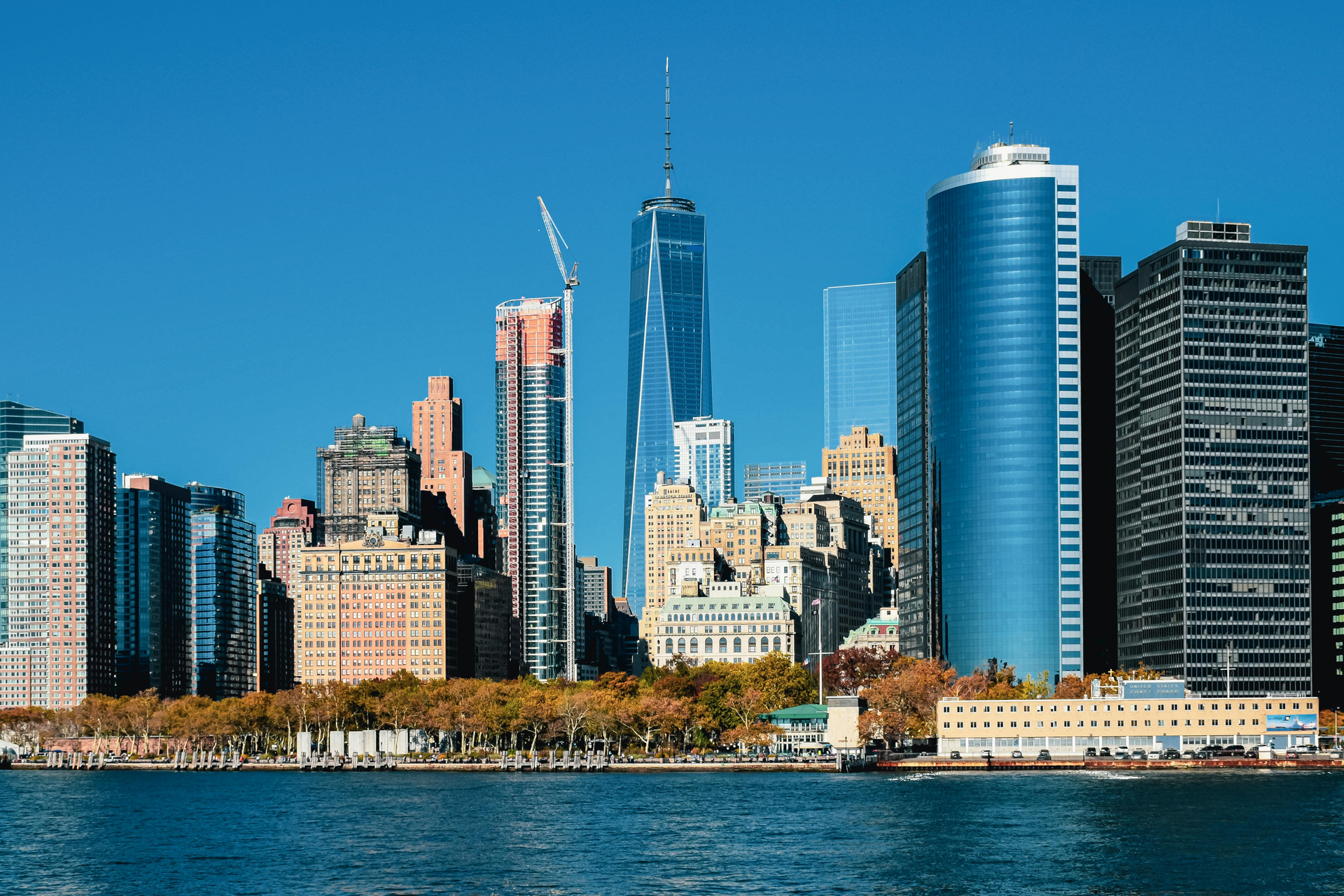 Modern waterfront city skyline with tall glass skyscrapers under a clear blue sky