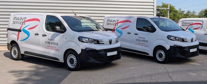 Three white delivery vans with red and black branding parked in a row outdoors.