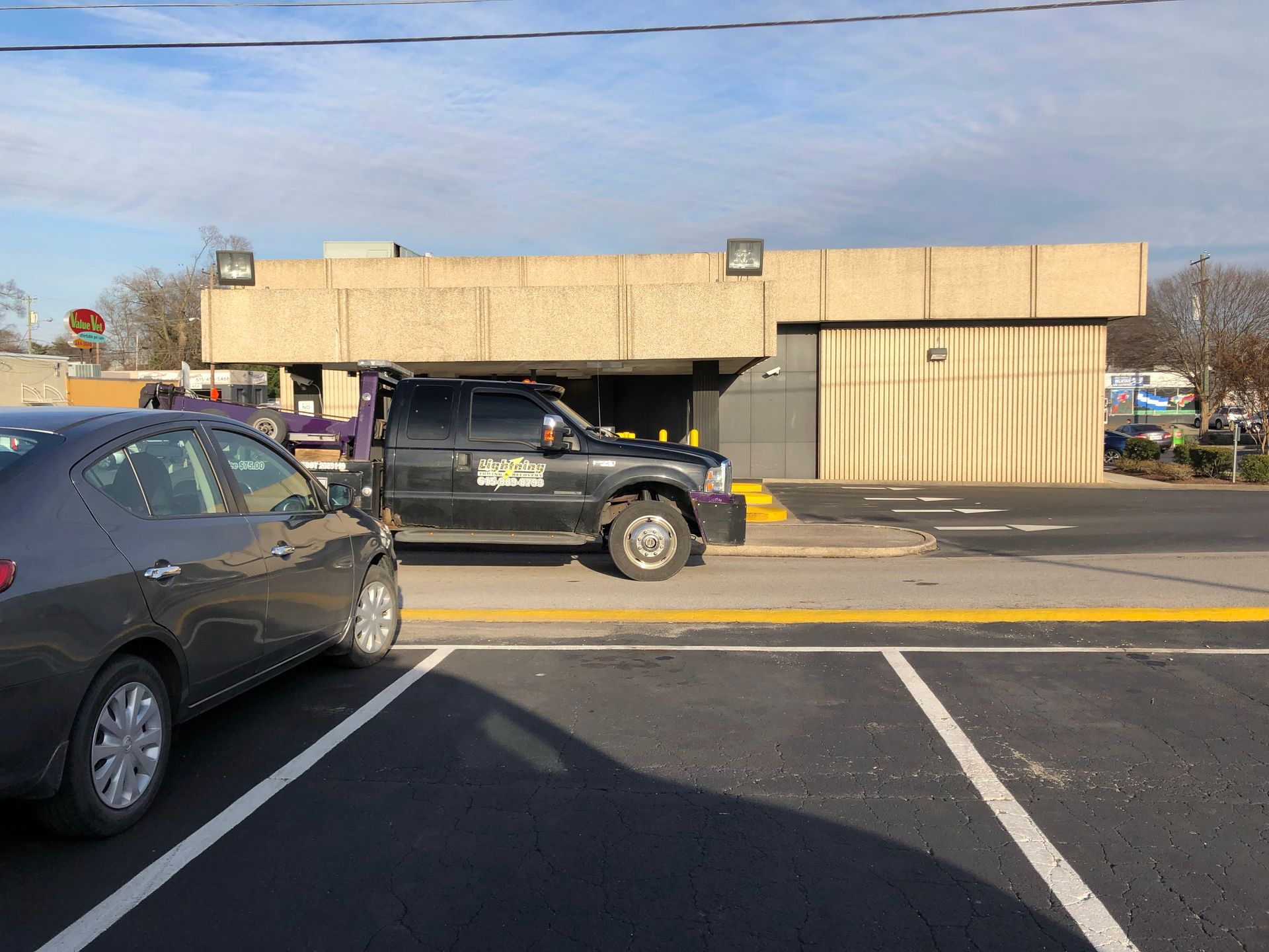 A car is parked in a parking lot in front of a building.