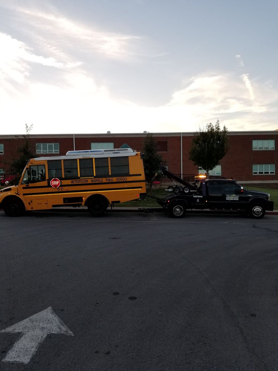 A school bus is being towed by a tow truck