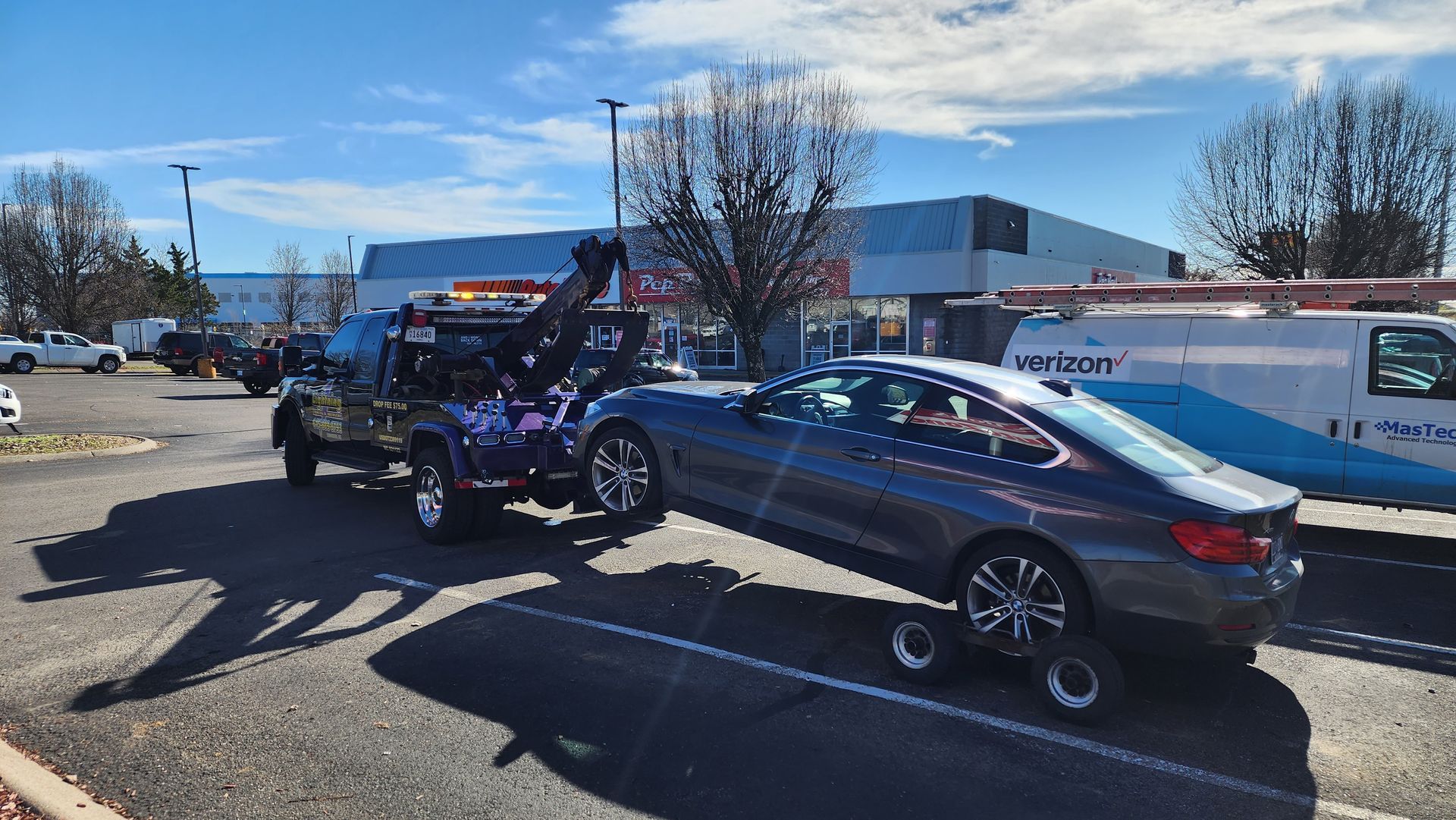 A tow truck is towing a car in a parking lot